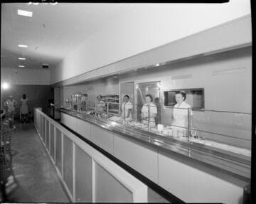 Cafeteria food service line with servers