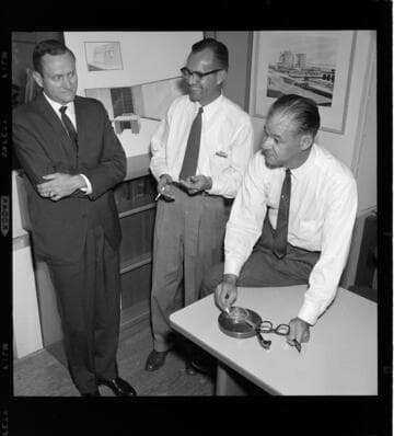Three men going over blueprints and an Organization Chart for the Montebello Commercial Districts