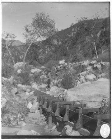 An unknown flume set in a canyon surrounded by trees and rocks