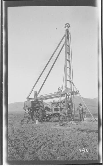 A working crew standing next to well drilling outfit in Tulare County