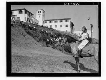 Boys riding horses toward campus buildings, Urban Military Academy, Brentwood, Los Angeles
