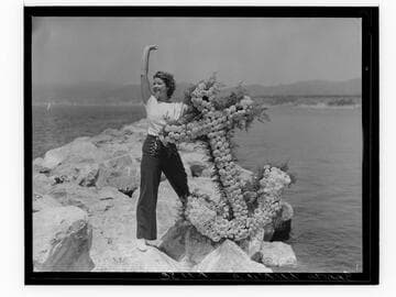 Woman posing with flower anchor on breakwater at the Yacht Harbor Breakwater Dedication, Santa Monica