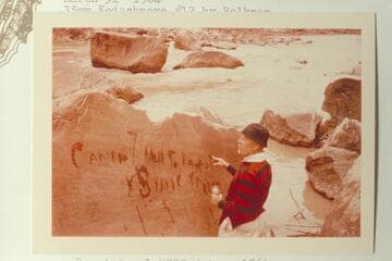 Dock Marston points up the Best Expedition inscription with water at Rapid 16, Cataract Canyon, Mile 204.55