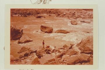 Rapid No. 16 in Cataract Canyon.  Dock Marston and Buzz Belknap are checking the Best and McDonald inscriptions.  The flat rock over Dock's head trapped the Best Expedition boat 1891, July 22.  Mile 204 1/2.  Rapid heads at 204.55