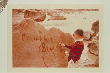 Dock Marston marking the inscription made by Harry McDonald of the Best Expedition after they locked a boat on the flat rock at upper left.  Mile 204 1/2 in Rapid No. 16