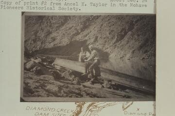 Emery Kolb and Reith Hyde pose for pictures while repairing the punt used to make the run from Diamond Creek to Spencer Creek to salvage the dunnage from the Hyde sweep-scow which was caught at Mile 237