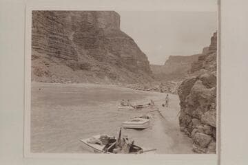 The beach below Mile 24.5 Rapid at Tanner Wash.  Stop of Nevills party for lunch on 7/13/47.  Francis Farquhar rigs tripod in boat in foreground, Garth Marston and Marjorie Farquhar on stern of boat in background and Margaret Marston on beach
