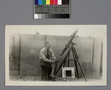Edwin Powell Hubble, seated next to a telescope, at Point Loma, California
