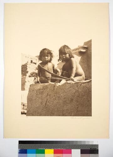 Two little Hopi boys in a pueblo, one holding bow and arrows