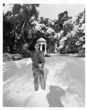 Irwin Morrkisch stands in front of a statue after snowfall, January 11, 1949