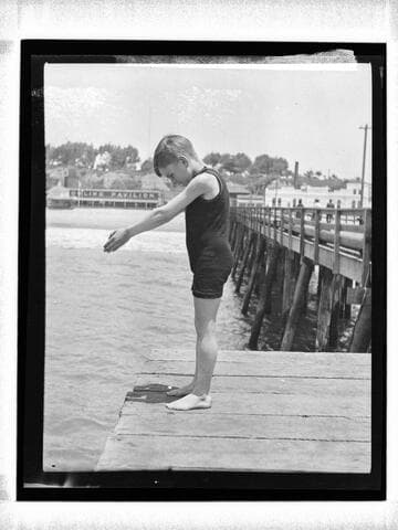 Boy in diving pose at end of North Beach Bath House Pier, Santa Monica