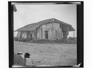 Dilapidated adobe with wagon next to it