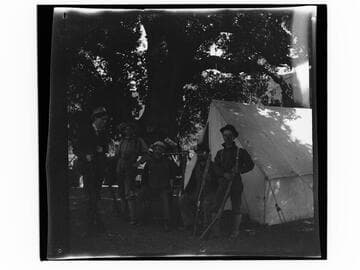 Group of men at camp with rifles