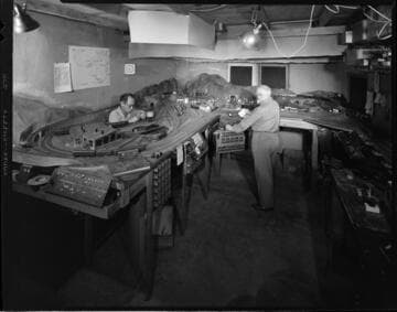 Men working with a large model railroad layout