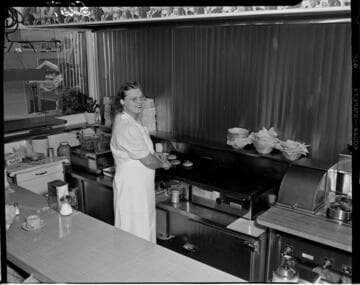 Lady cooking burgers on grill in a coffee shop