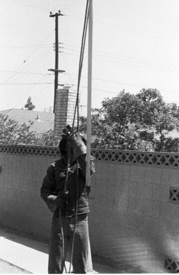 Lineman on pole and apprentice on ground supplying equipment and tools to lineman