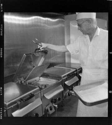 Man preparing chicken dinners for "Chicken Delight" take-out