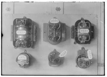 Six electric meters mounted in a group.  All are different designs