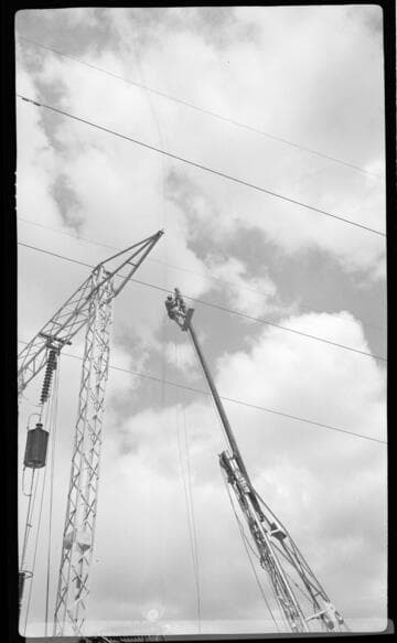 Lineman on crane boom working on transmission tower