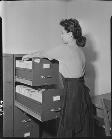 Secretary working with file drawer cabinet with both top drawers open at the same time