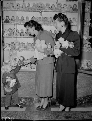 Two ladies and a little girl with two dolls at Christmas display