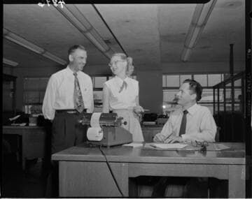Three office workers talking at desk