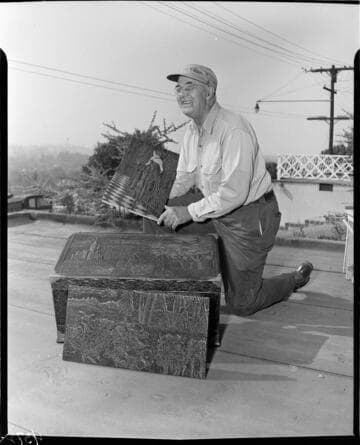 Man holding carved pieces of wood art from his hobby