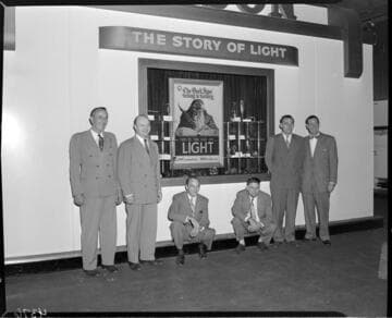 Edison display booth exhibiting the "Story of Light" with six men posed in the shot