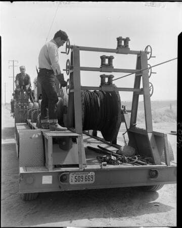 Men running conductor pulling machine