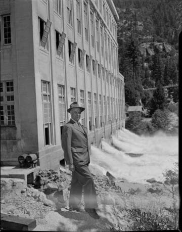 Dave Redinger (in suit and hat) standing near the tailrace at Powerhouse #1